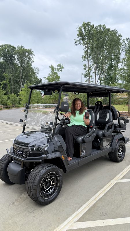 A woman seated in a new black six-seat lifted golf cart