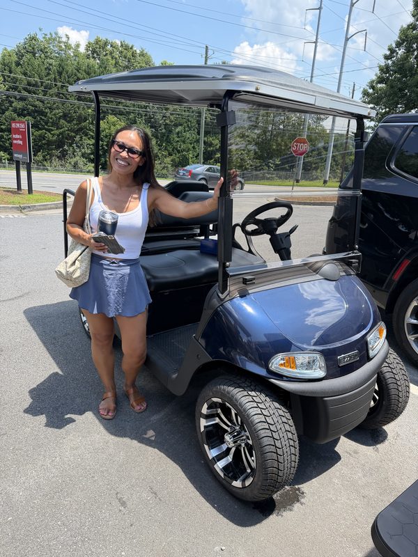A woman beside a navy blue golf cart at the Prime Golf Carts showroom