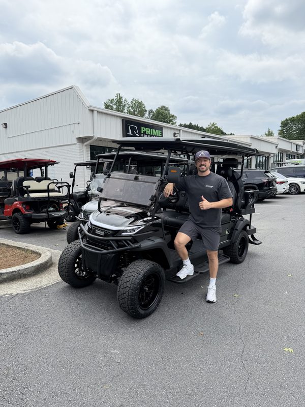 A man beside a new black lifted golf cart outside the Prime Golf Carts showroom