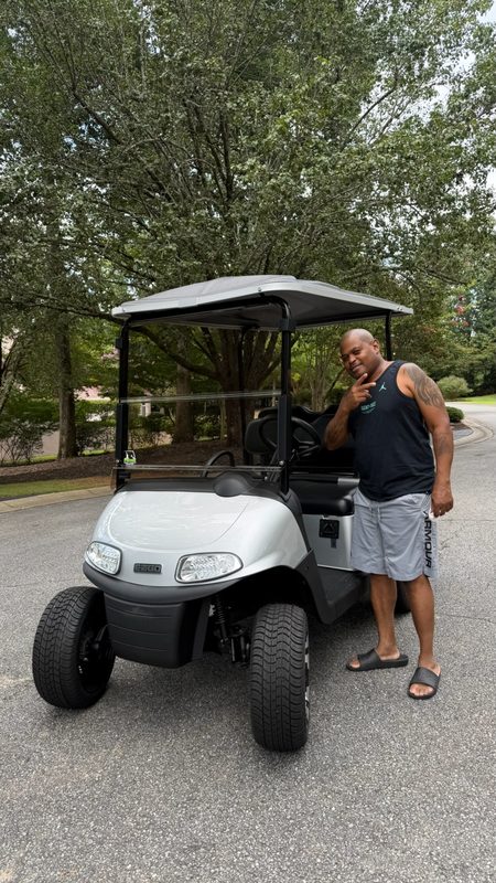 A man giving a thumbs up beside his new cream coloured golf cart in a driveway