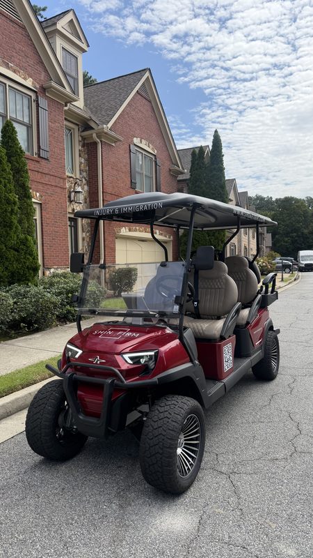 A new red lifted golf cart parked in the driveway of a brick home