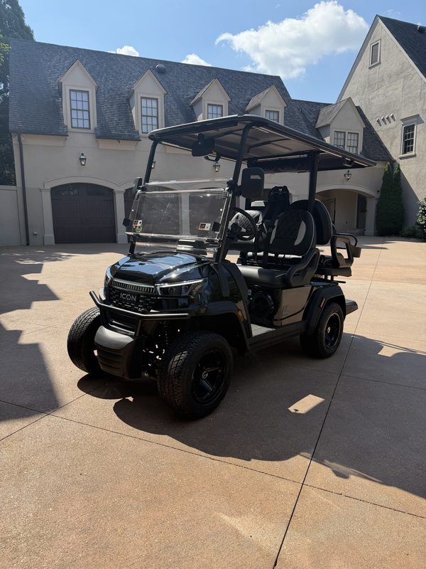 A new black lifted golf cart parked in a residential driveway