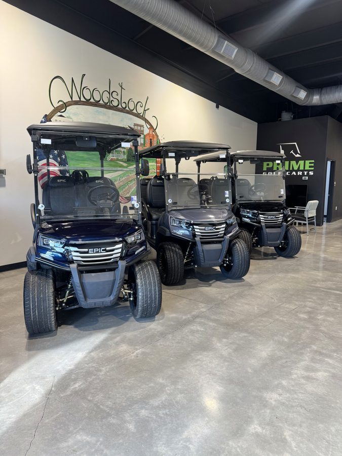 Inside the Prime Golf Carts of Woodstock showroom, with three EPIC lifted golf carts parked beneath a hand-painted Woodstock mural
